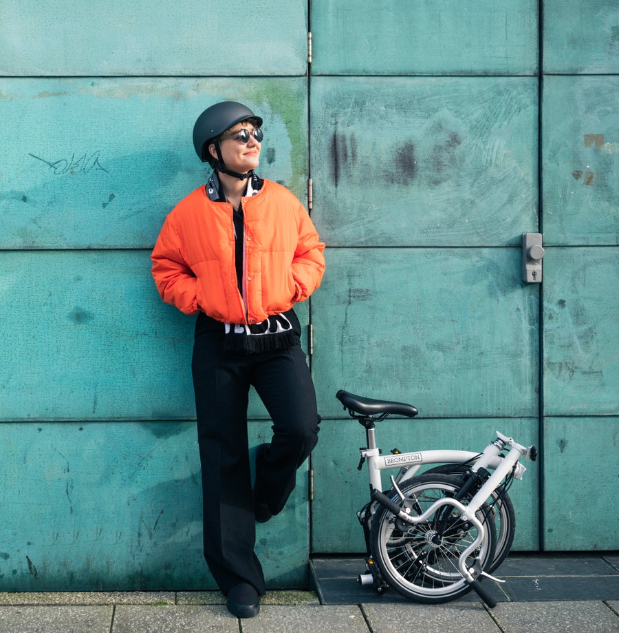 A happy person smiling with their Brompton folded bike