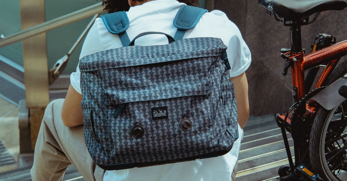 an overhead shot of a model riding a Brompton with a Brompton Backpack made with Liberty Fabric