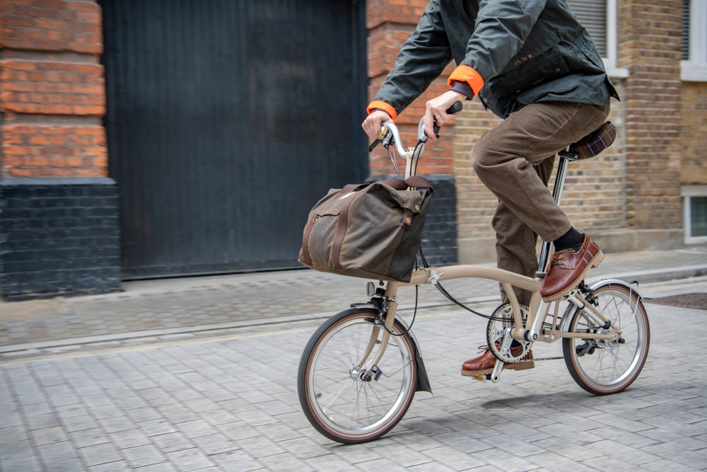 Two women on Barbour x Brompton C Lines riding through the forest in Barbour x Brompton jackets