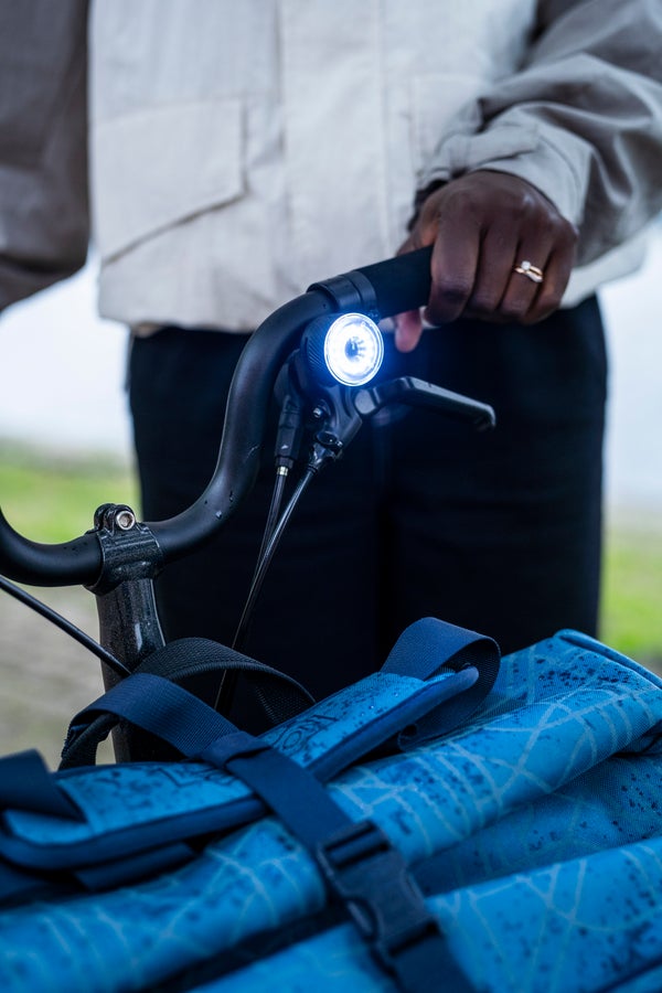 A close up photograph of a model holding the Brompton folding bike handlebars with Be Seen Lights