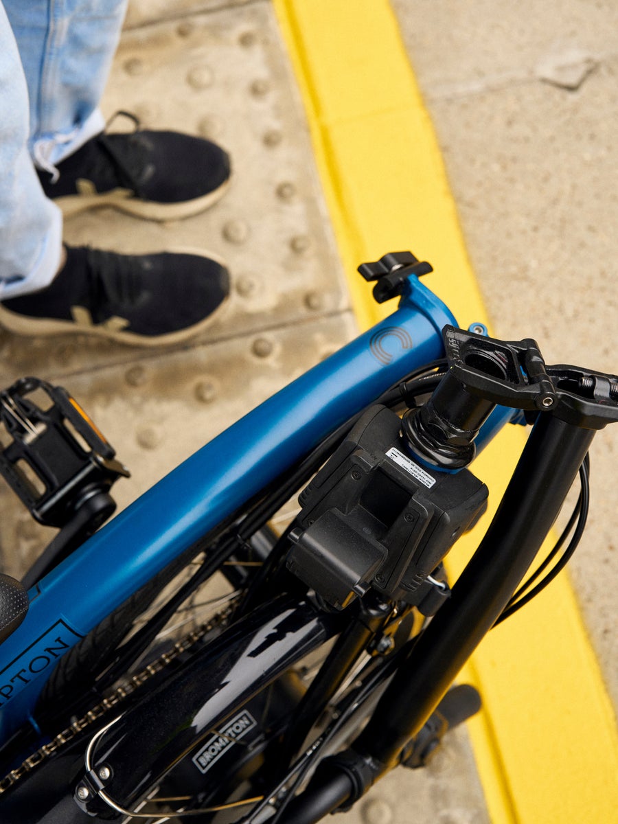 A folded Ocean Blue C Line Brompton bike on a train platform