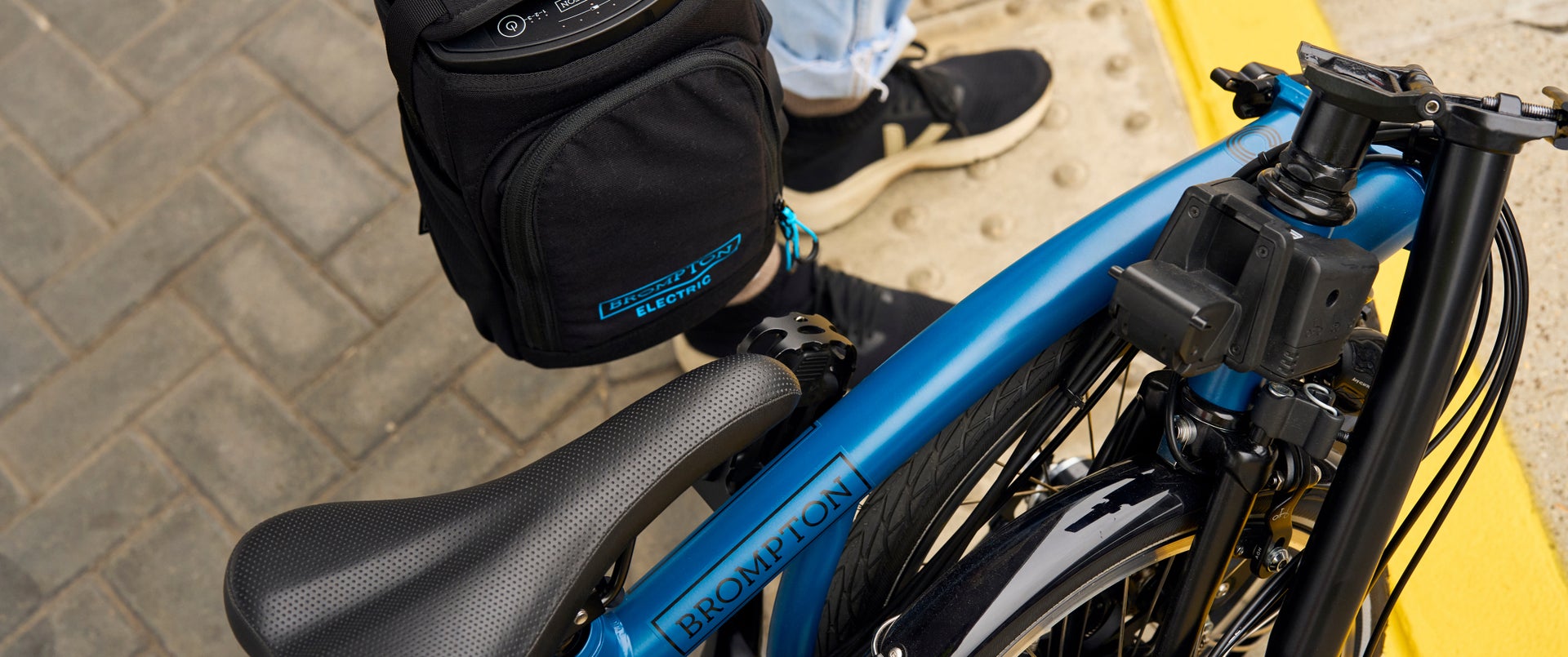 A folded Ocean Blue C Line Brompton bike on a train platform