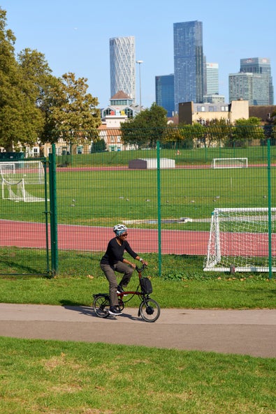 person riding an electric p line brompton through a park