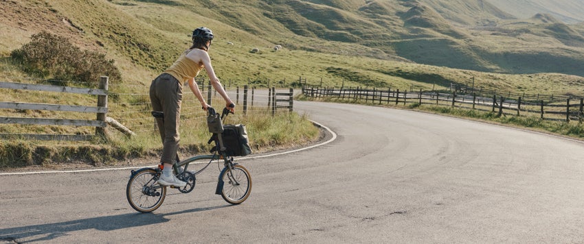 person cycling a brompton beyond collaboration bike in countryside