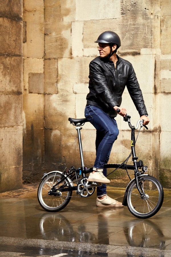 A stylish man on a Brompton folding bike wearing a Dashel Helmet