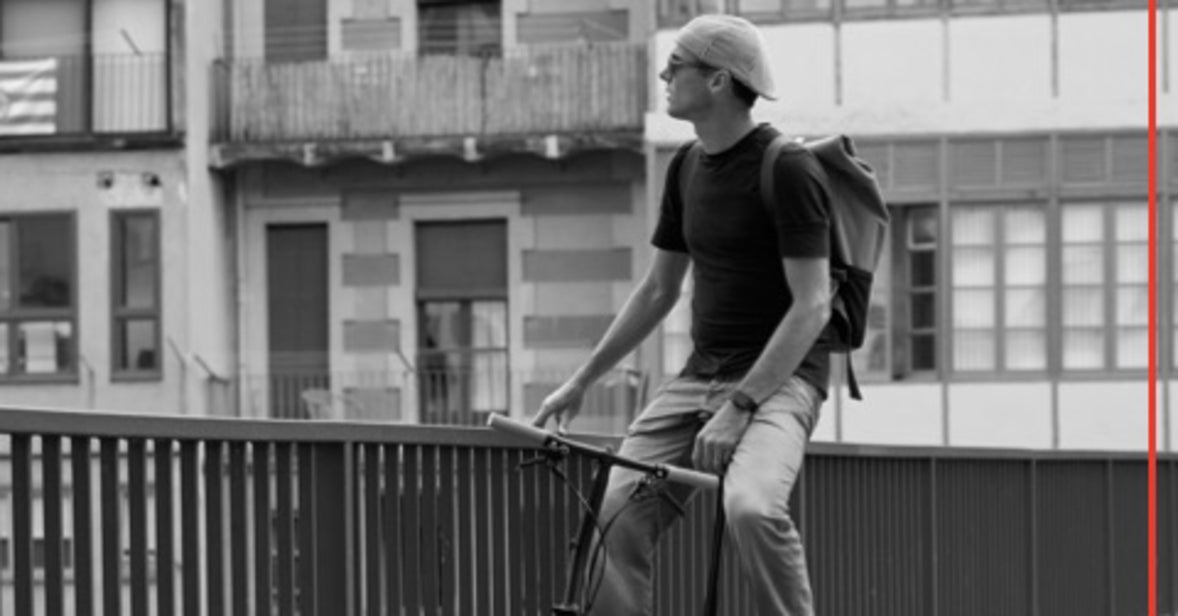 A black and white photograph of David Millar overlooking a bridge on his CHPT3 Brompton bike