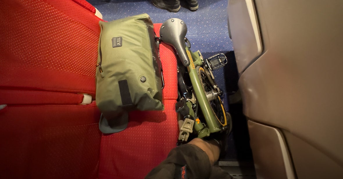 The Brompton x Bear Grylls folding bike packed down on a train with the Brompton x Bear Grylls luggage