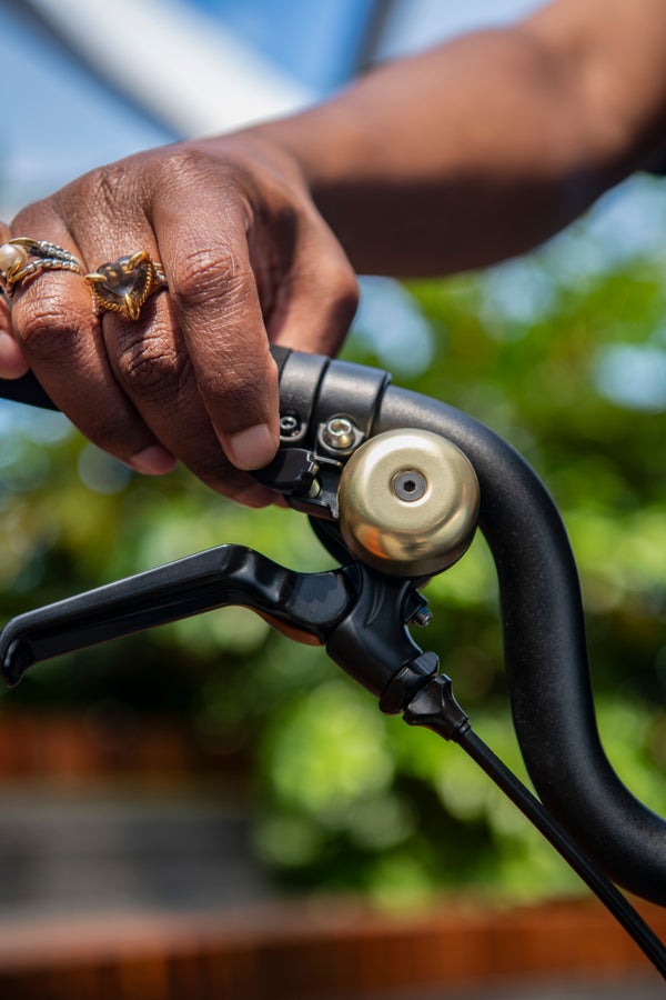 A person's hand on a Brompton folding bike handlebar ringing a brass bell