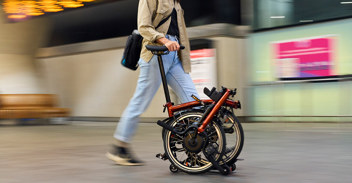 Woman pushing folded Brompton bike