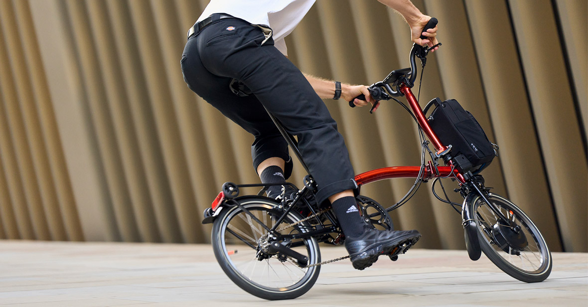 Woman sat on step with folded electric Brompton