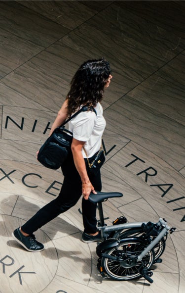 A woman gliding a Brompton P Line through Moynihan Train Hall in NYC