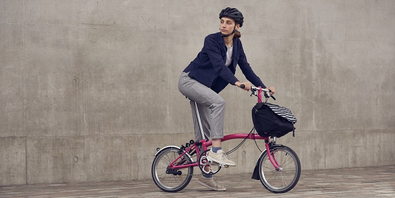 Person riding Brompton bike wearing a helmet